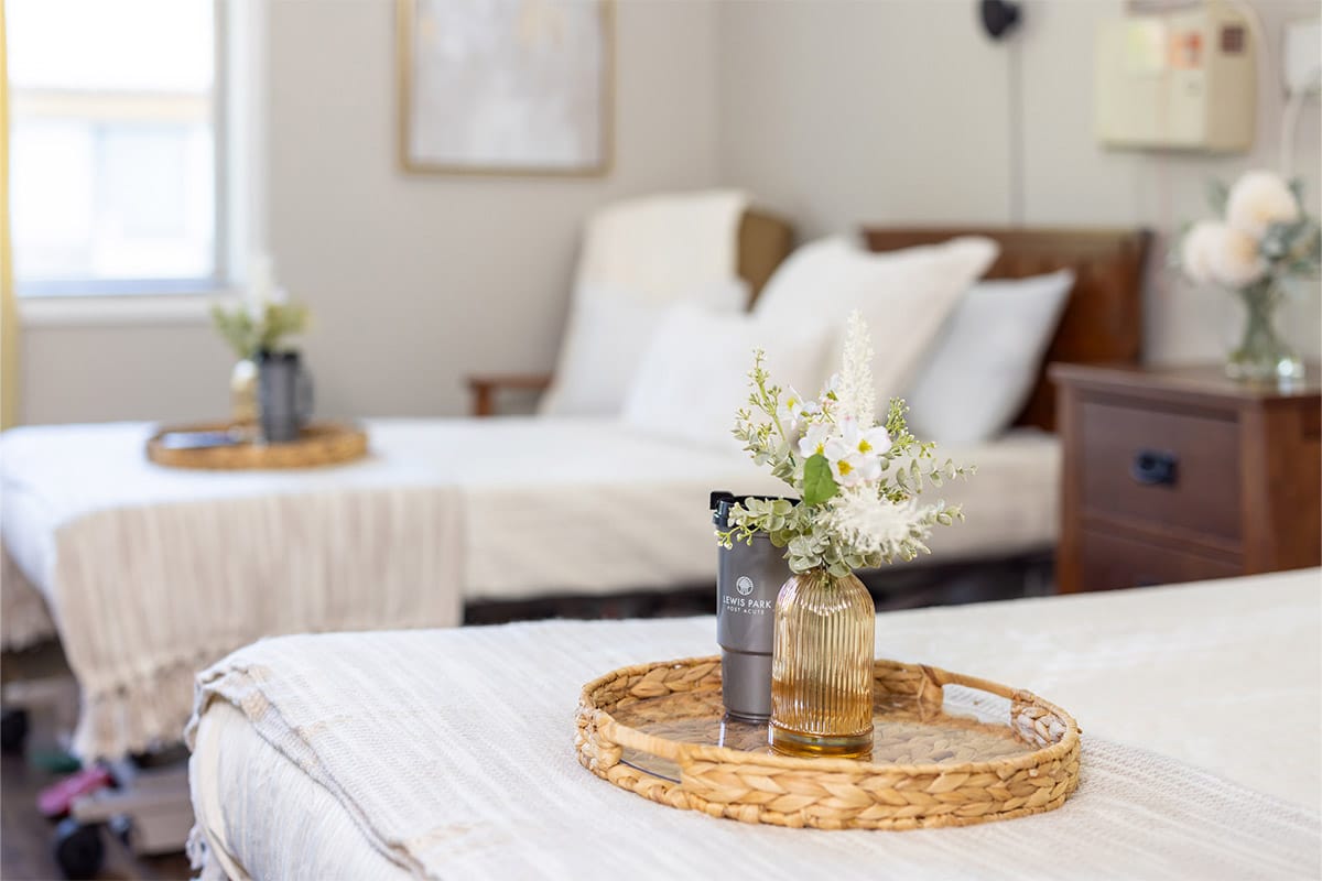 Flowers and water cup on tray on bed at Lewis Park Post Acute